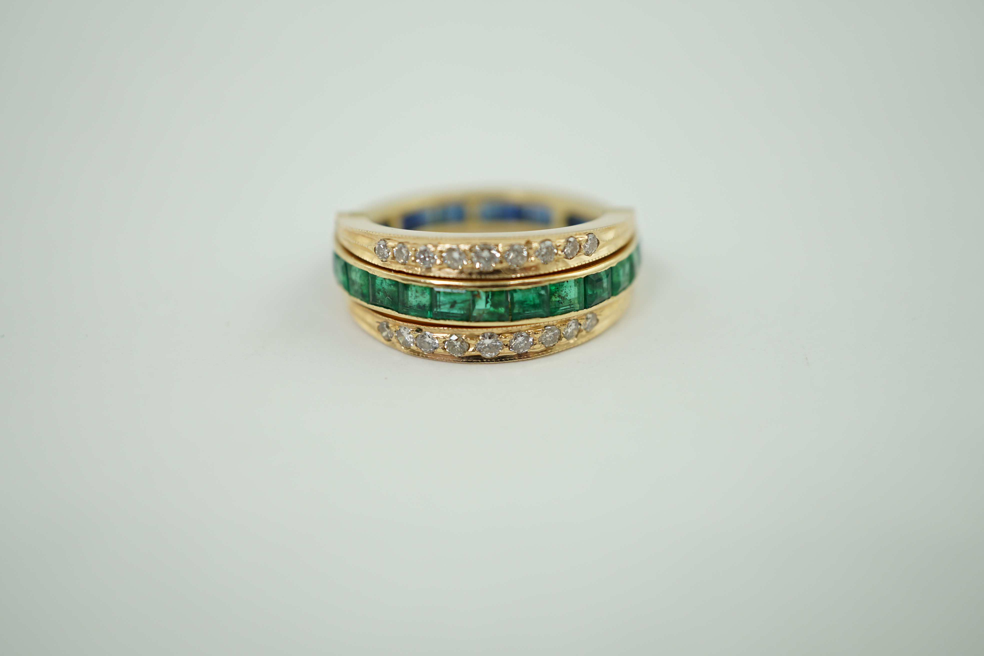 A recent gold, emerald, sapphire and diamond set triple band swivelling eternity ring